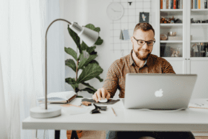 Young man working on his laptop reading the guide to a one person business model.